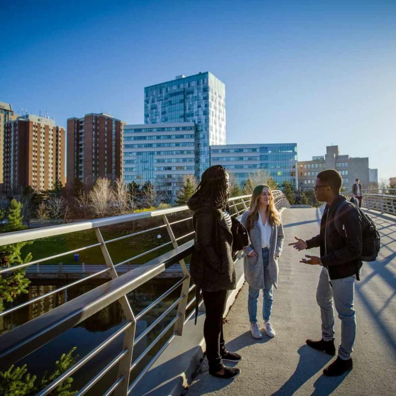 Trois étudiants à l'extérieure sur un pont devant le Pavillon des Sciences sociales. 