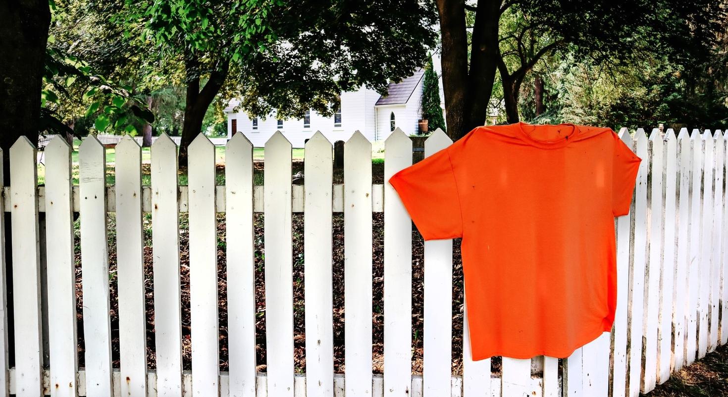 Chandail orange sur clôture blanche