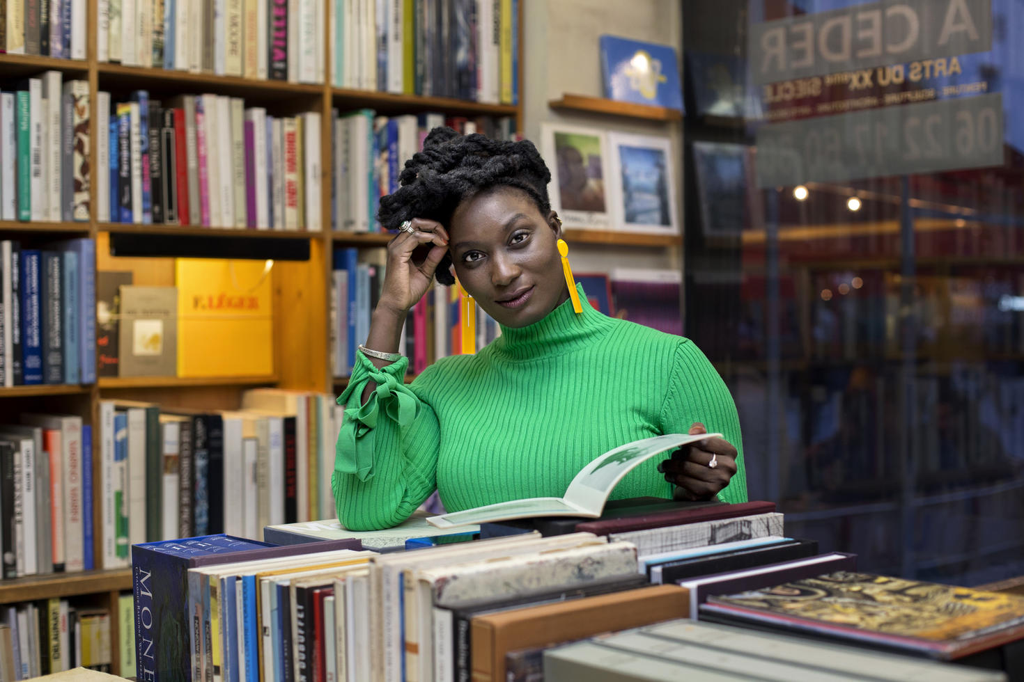 Personne debout dans une bibliothèque en train de lire un livre.