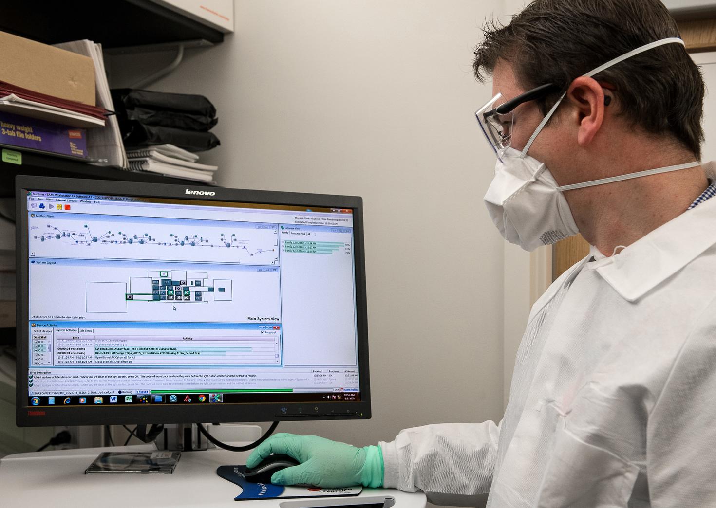 Man wearing mask and gloves works on computer