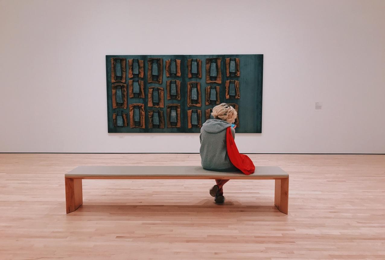 Une personne assisse sur un banc dans une gallerie d'art