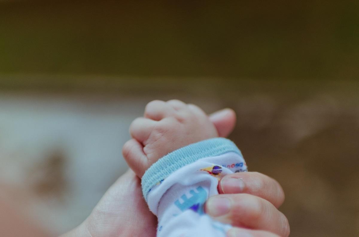 Main du bébé tenue par un adulte