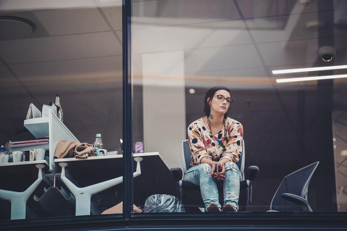 Jeune femme en manque d'inspiration regardant longuement par la fenêtre d'un bureau