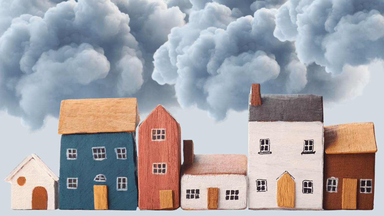Une rangée de petites maisons en bois, colorées et de tailles variées. En arrière-plan, de lourds nuages sombres envahissent le ciel.