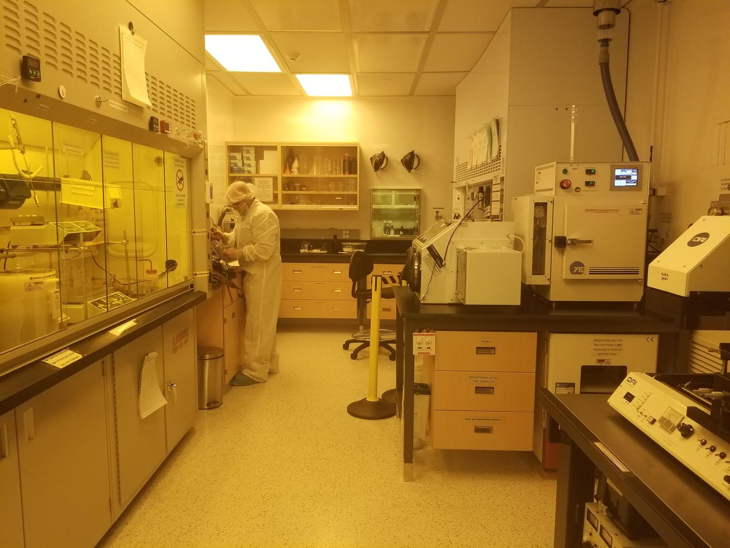Scientist dressed in clean room attire working among various tools in a lab