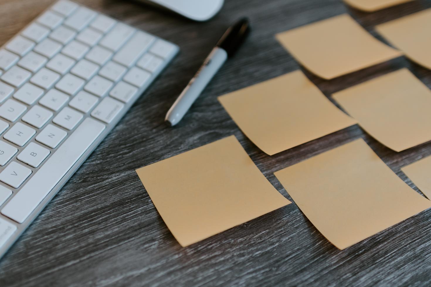 close up on a keyboard and blank sticky notes on a desk