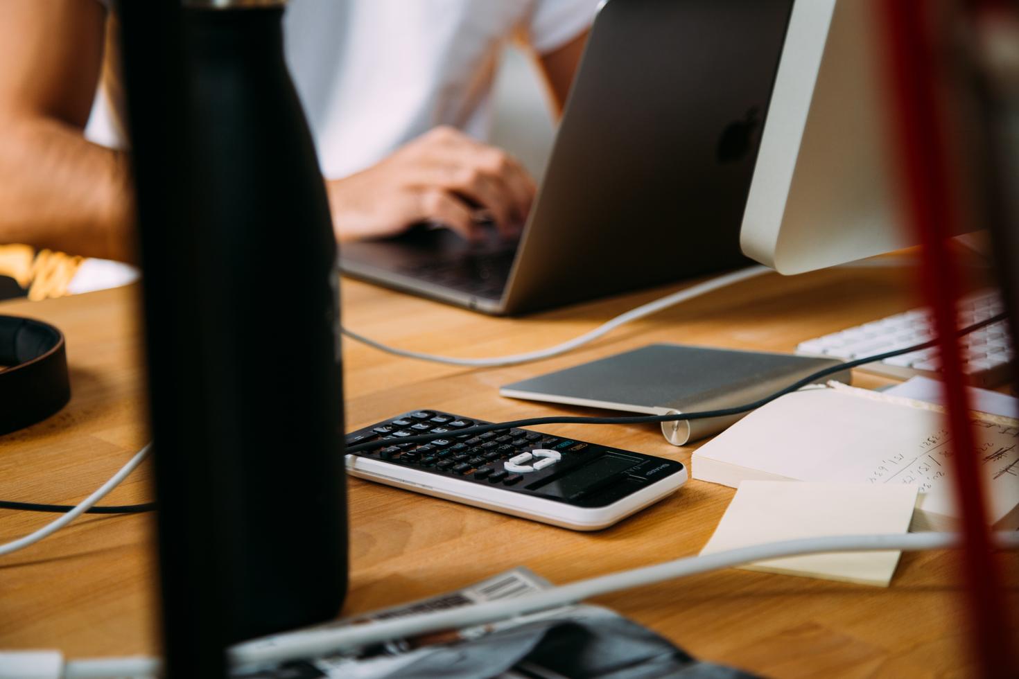 laptop with papers and calculator on a table