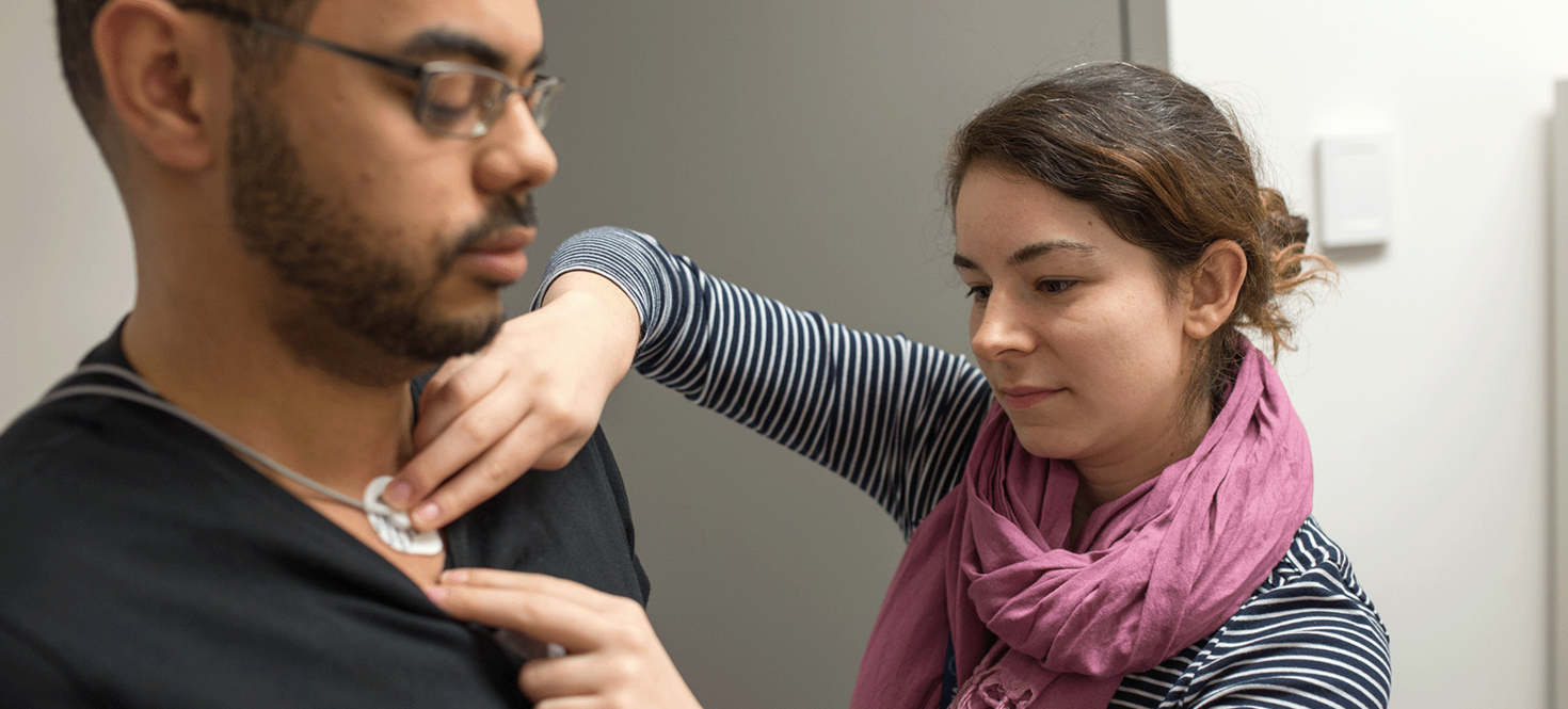 Woman applying electrodes on male subject.