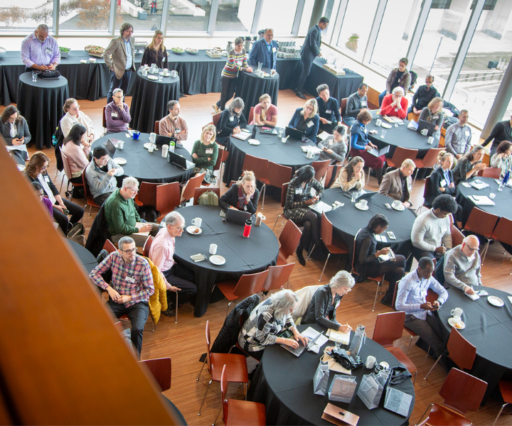 A crowd of people sitting at conference tables, seen from above.