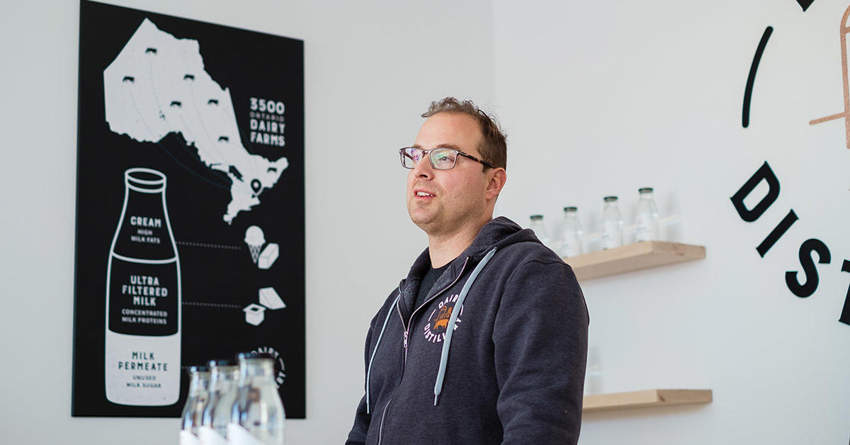 portrait of Omid Mcdonald as he stands in at the bar of the Dairy Distillery
