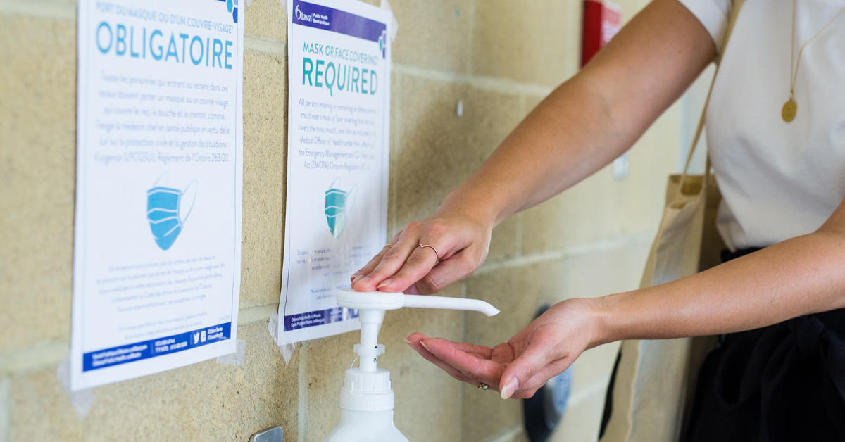 Une personne appuie sur ue pompe de gel désinfectant pour les mains