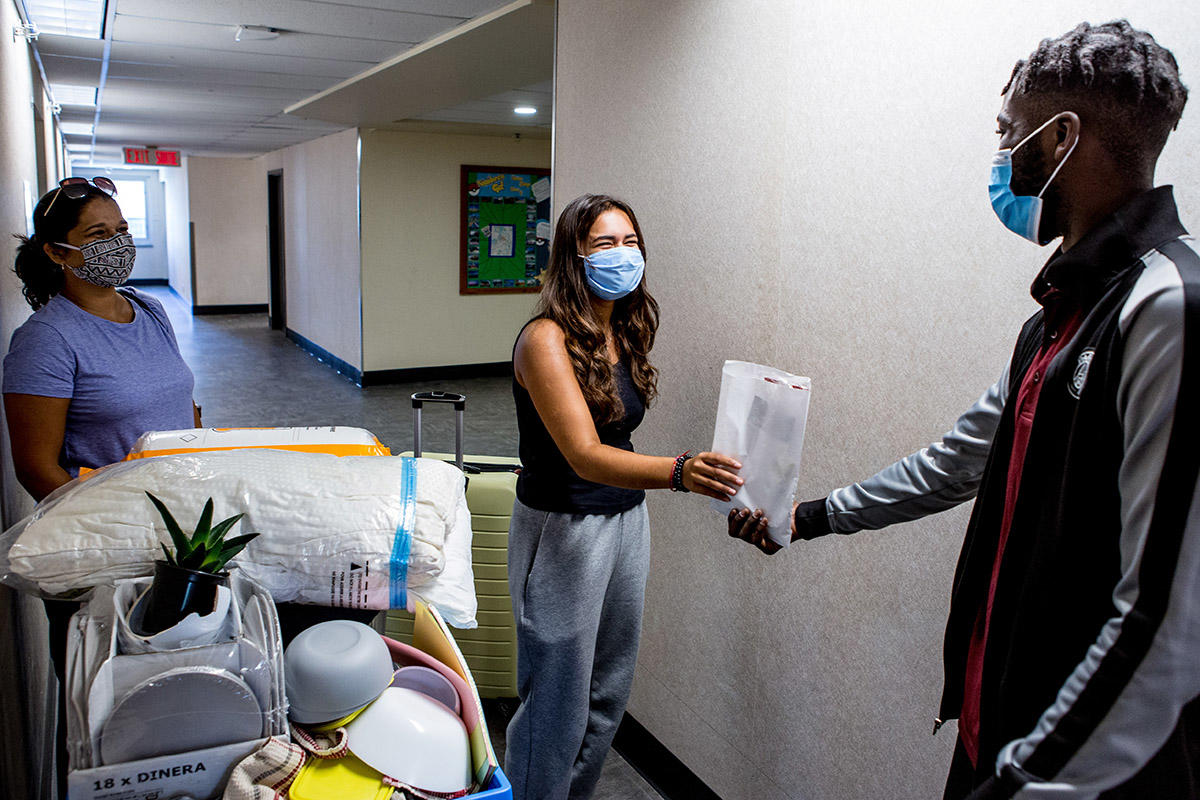 Resident advisor Tij hand delivers welcome kit to new student.