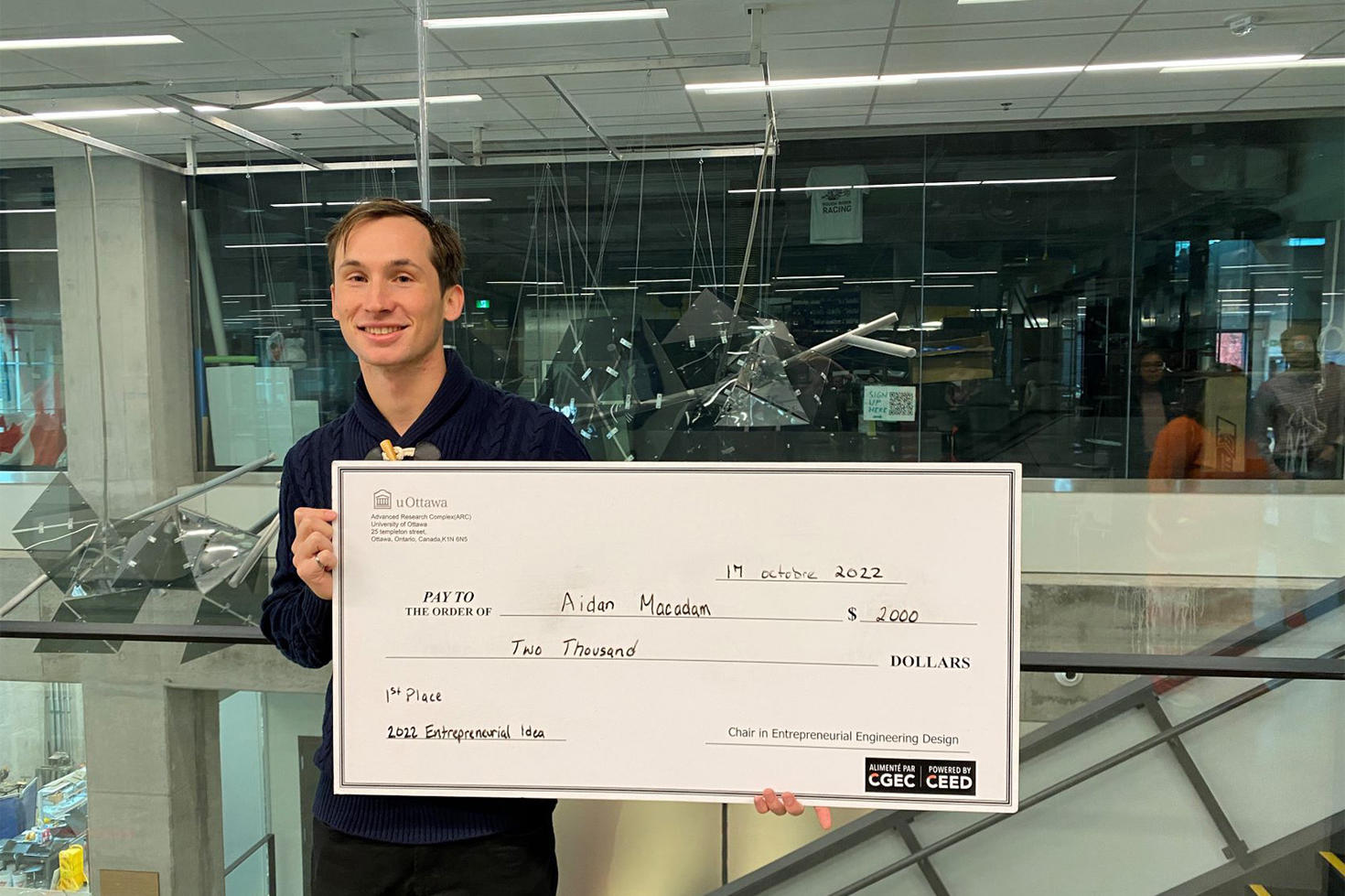 Engineering student Aidan MacAdam holds a $2000 check.