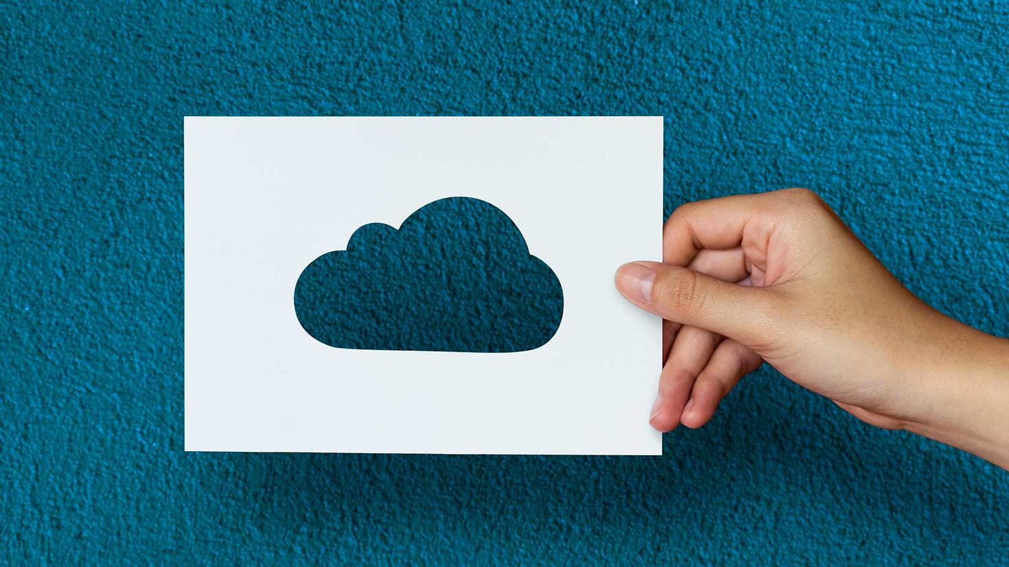 Une main qui tient un nuage en carton pour illustrer le stockage infonuagique