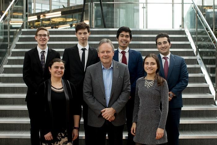 A group of people pose in front of a set of stairs.