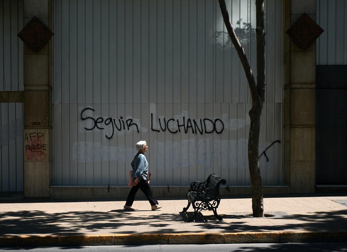 older man walking past graffiti reading 'keep fighting' 