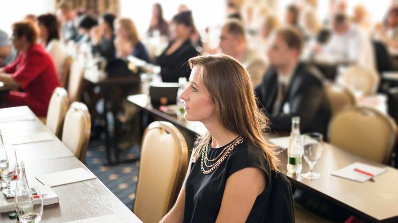 a picture of a woman listening to a conference