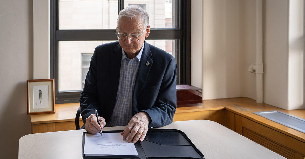 President Jacques Fremont signs Scarborough charter at desk in office