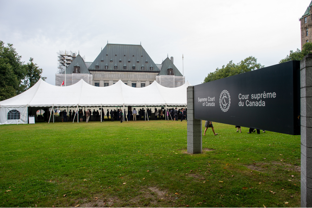 A large white event tent set up on the lawn in front of the Supreme Court of Canada