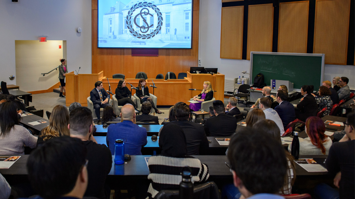 classroom full of people with 3 students and 1 judge seated at the front of the room