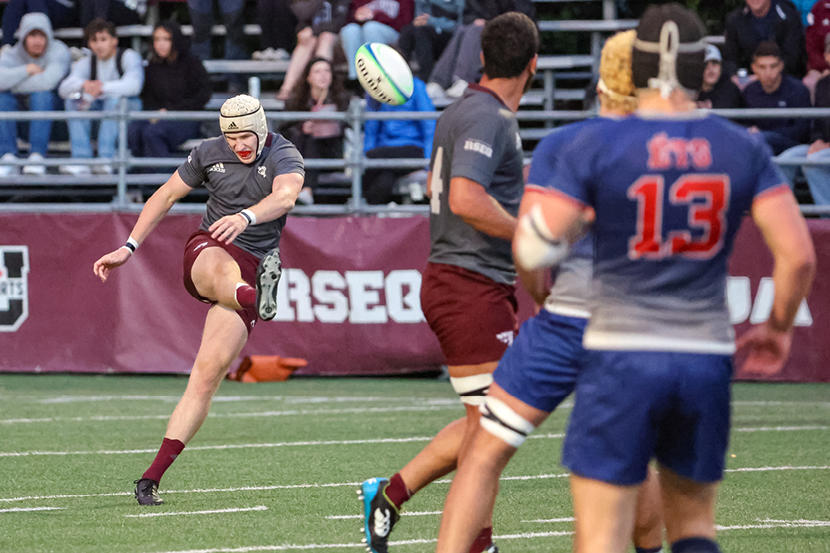 Un joueur de rugby des Gee-Gees botte le ballon vers les joueurs adverses pendant un match.
