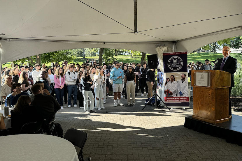 The dean of medicine addresses a group of students outdoors