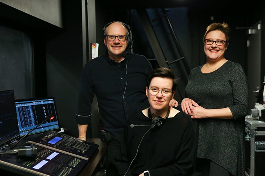 A group of three people in front of a computer, working on a production.