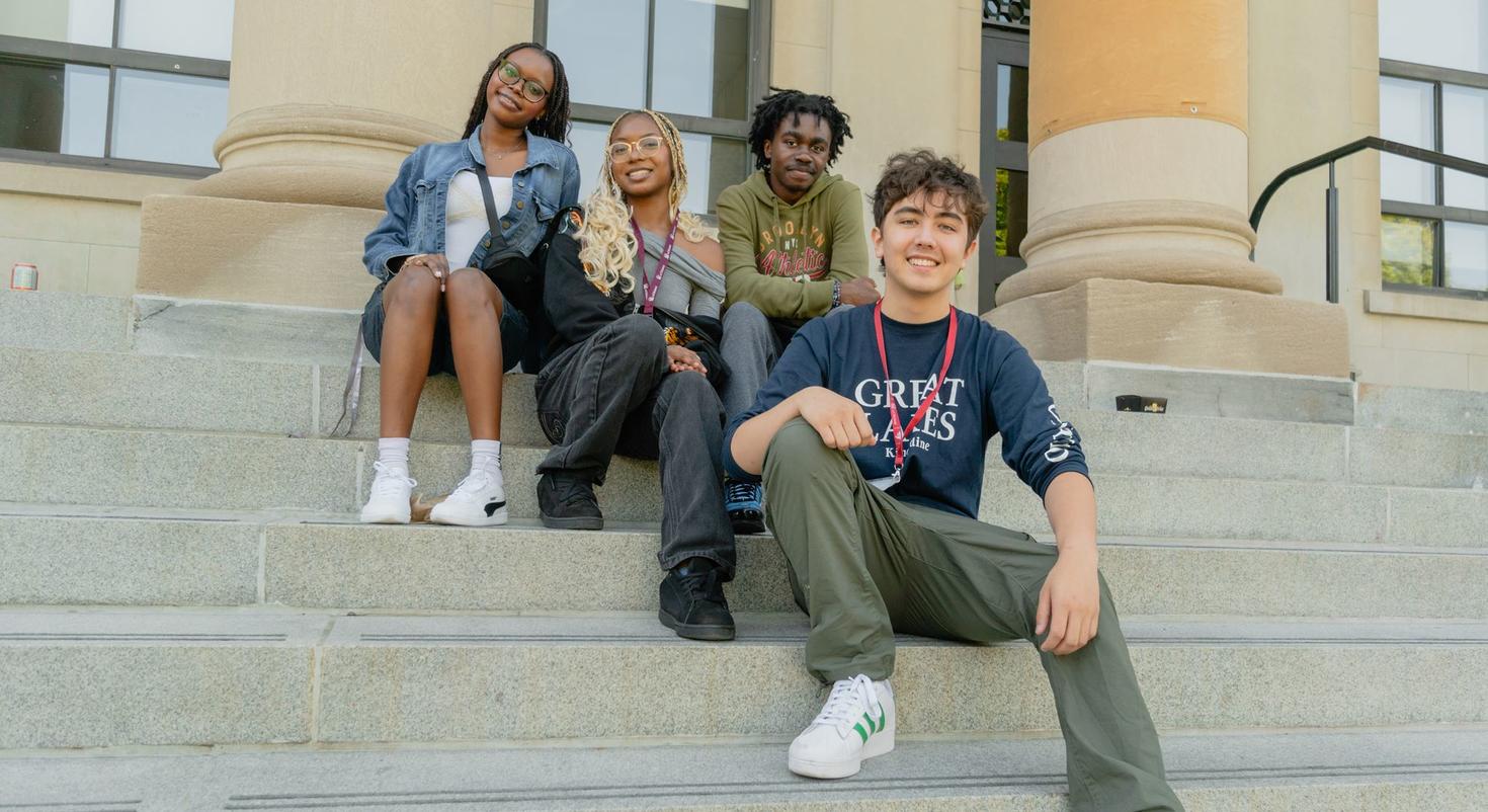 Un groupe de quatre étudiantes et étudiants étrangers assis sur les marches de Tabaret Hall.