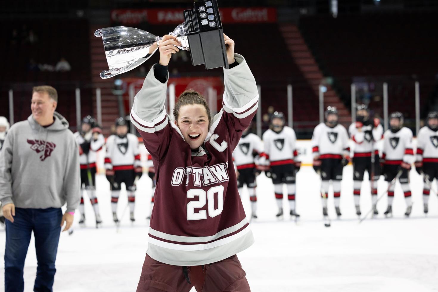 Une joueuse de l'équipe féminine de hockey des Gee Gees brandit le trophée de la Coupe Alerts.