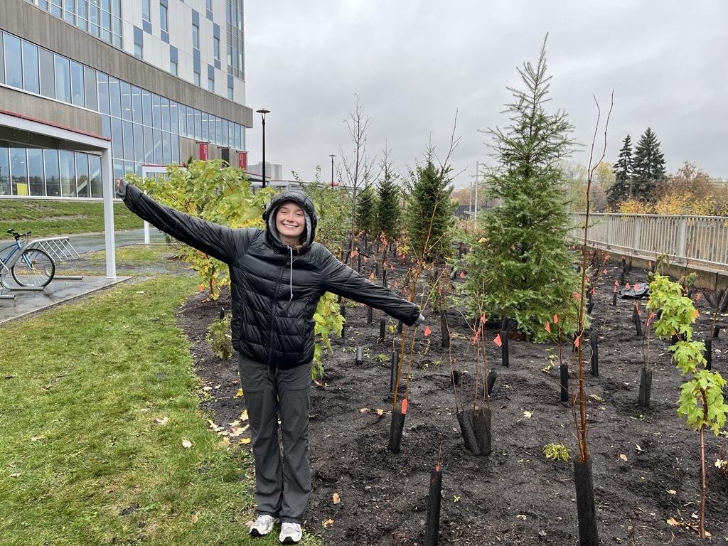 Student smiling standing beside the tiny forest