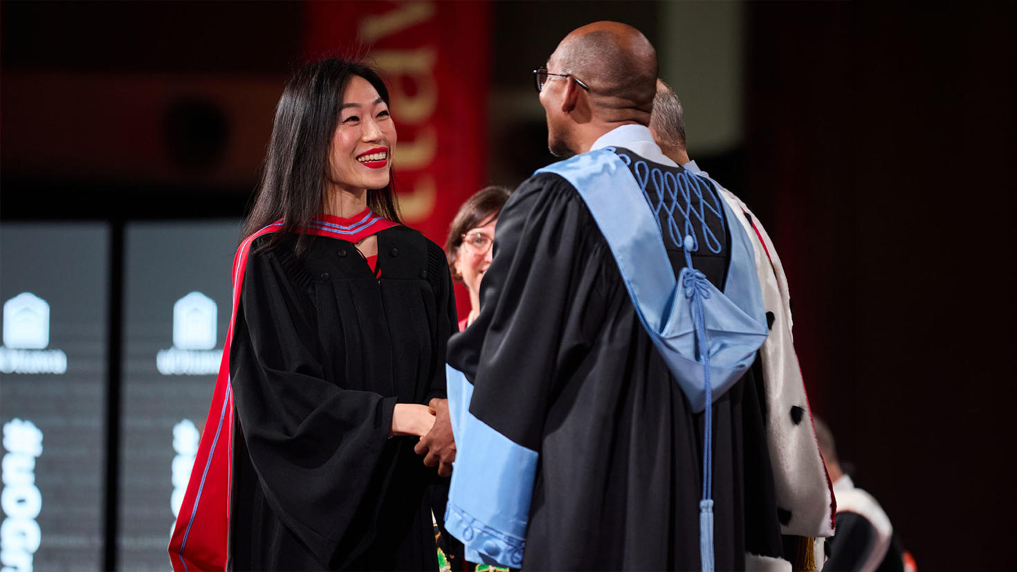 Une nouvelle diplômée serrant la main du doyen de la faculté