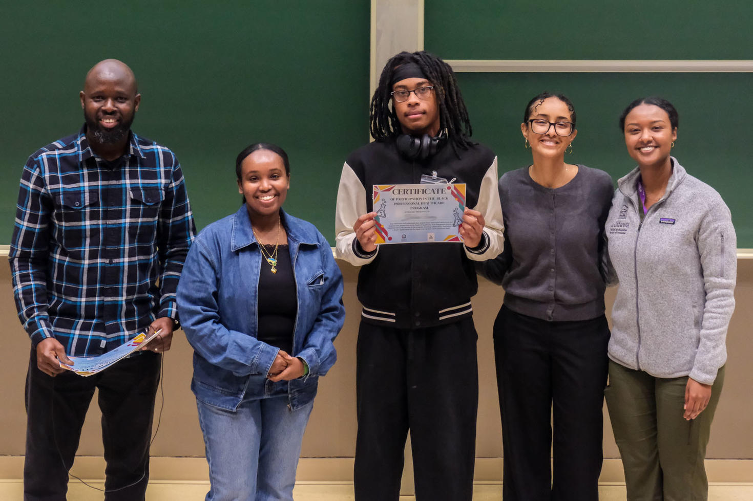 a guidance counsellor and three student teachers flank a student who holds a participation certificate.