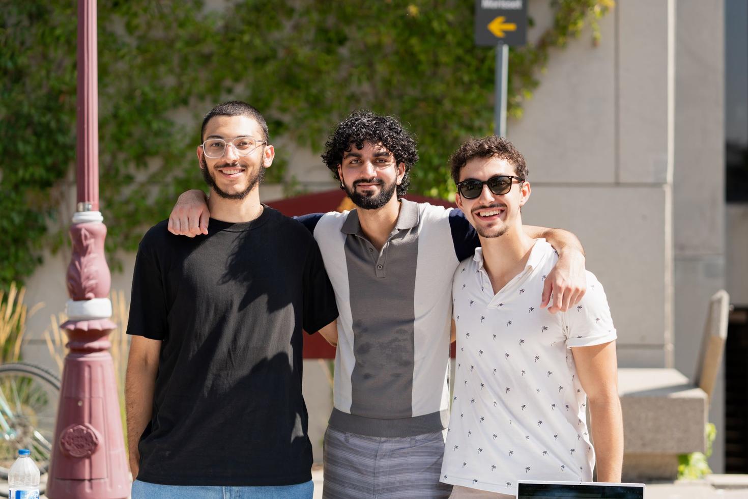Trois étudiants membres d'un club se tiennent bras dessus bras dessous lors du Salon des clubs 2023 à l'Université d'Ottawa.
