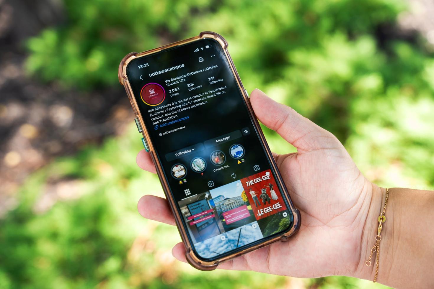 Une main tenant un iPhone sur lequel s'affiche le compte Instagram @uottawacampus.