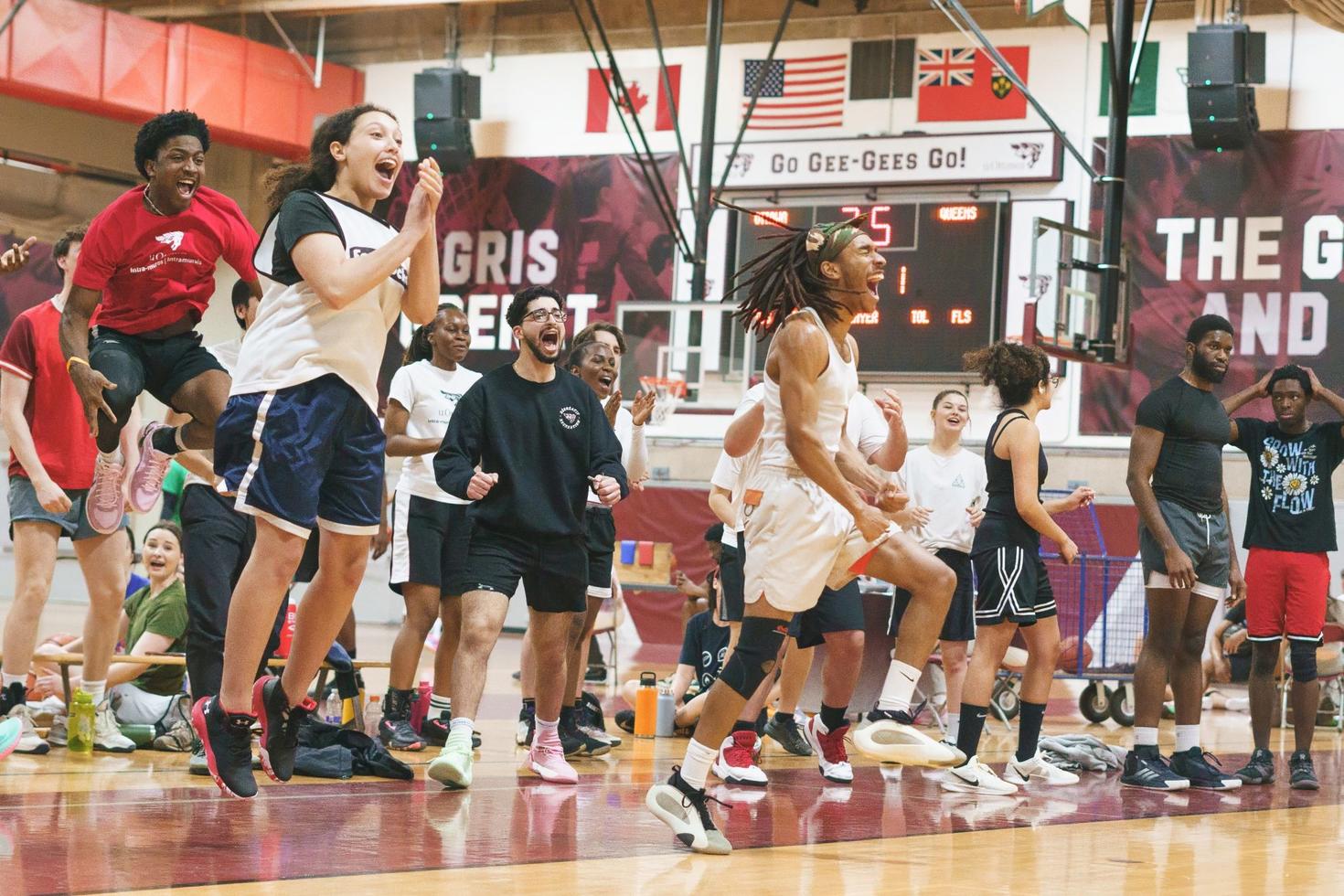 Les joueurs et joueuses de basket-ball des intra-muros à l'Université d'Ottawa sautent de joie sur le bord du terrain lorsque leurs coéquipiers marquent des points.