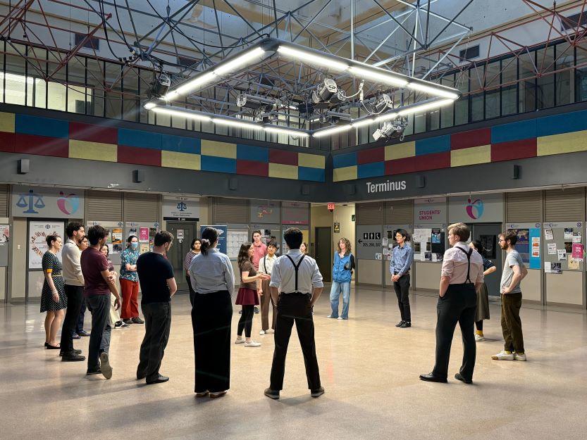 Des étudiantes et étudiants danseurs du club uoSwing sont debout en cercle dans une salle de répétition.
