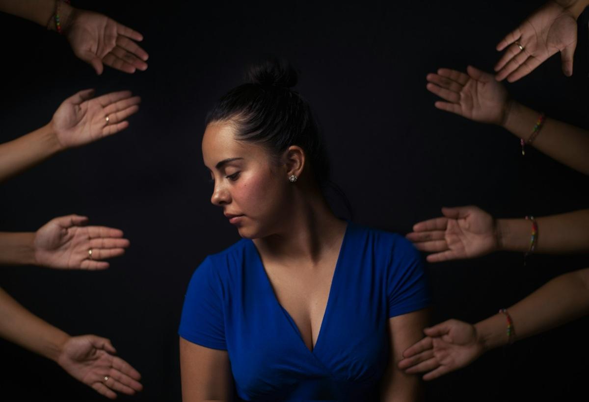 Une femme entourée de mains qui s’agitent dans tous les sens