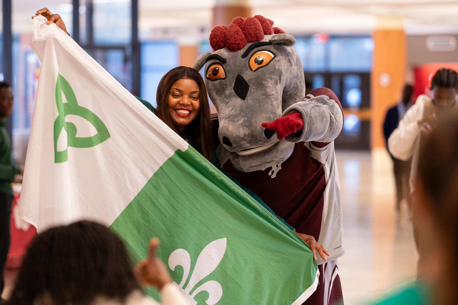 étudiante qui pose avec la mascotte des GeeGees et un drapeau franco-ontarien