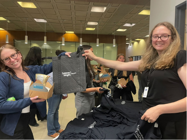 Membre féminin du groupe étudiant remettant un sac à une autre étudiante.