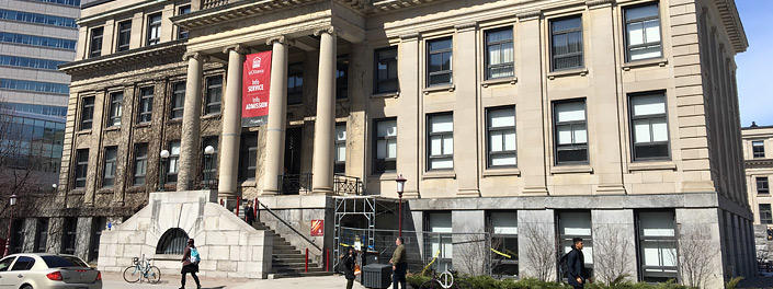 People walk along Laurier Avenue in front of Tabaret Hall and one of its covered entrances.
