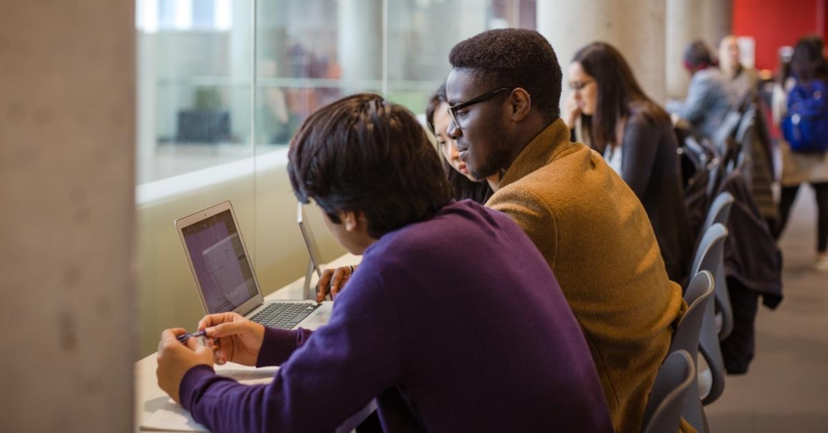 Group of students working on a laptop in a common area.