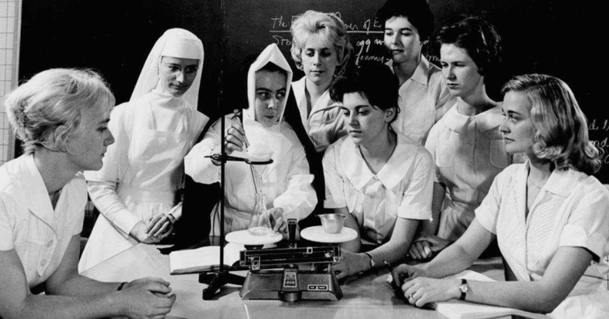 Archival photo of a group of women in a chemistry class observing a chemical reaction.