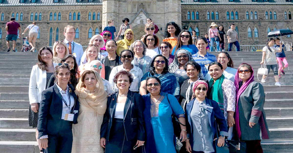 Une vingtaine de personnes, majoritairement des femmes, se tiennent devant les marches de l’Édifice du Centre.