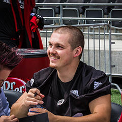 Lewis Ward assis à une table signe des autographes pour les supporteurs.