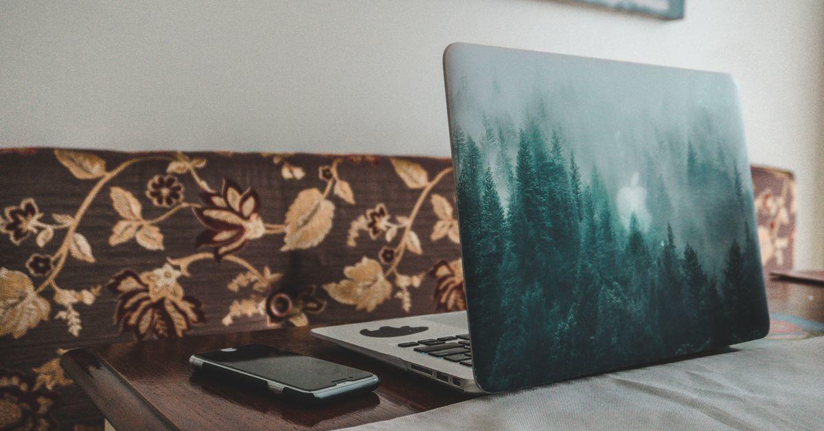 An open laptop is placed on a dining room table.