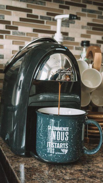Coffee is dripping in a mug from a coffee maker.