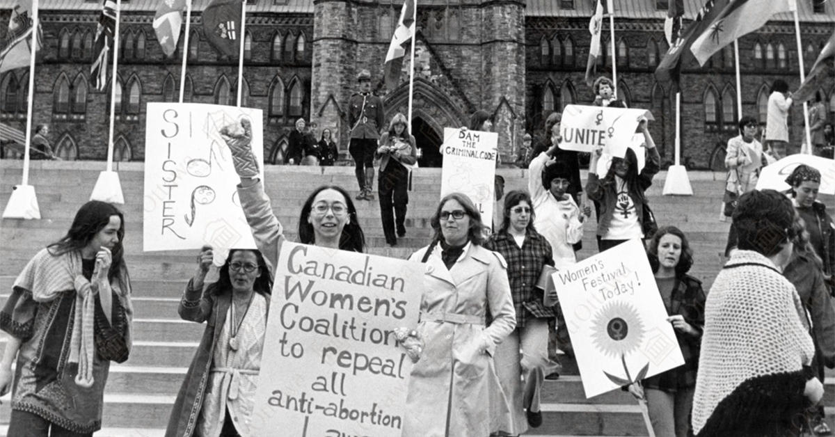 Black and white archival photo of women marching on Parliament Hill