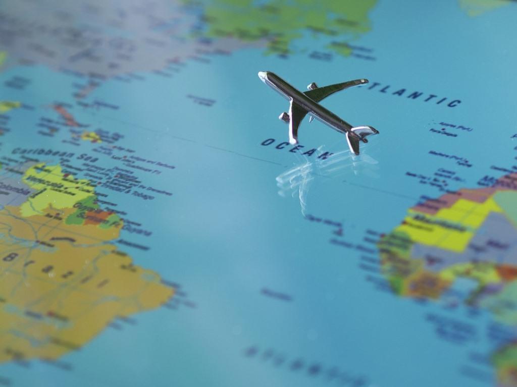 Small metal model airplane flying over a flat world map. 
