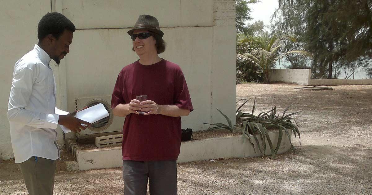 Two men stand outside a building in Senegal.