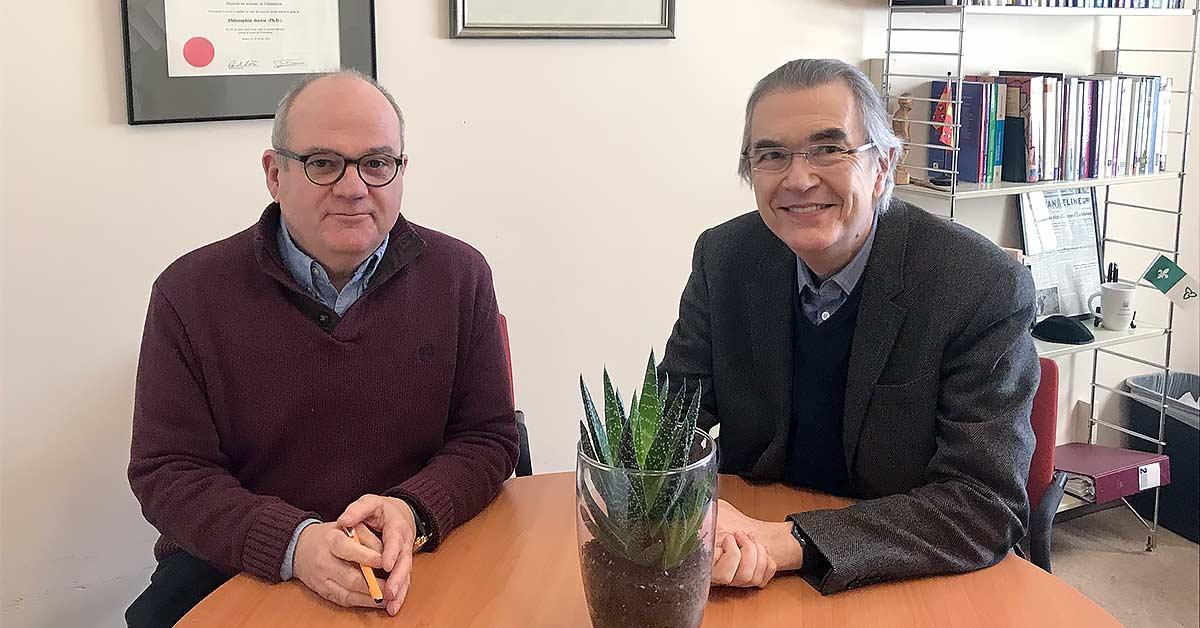 André Samson and Philippe Robaey sit together at a table in an office.